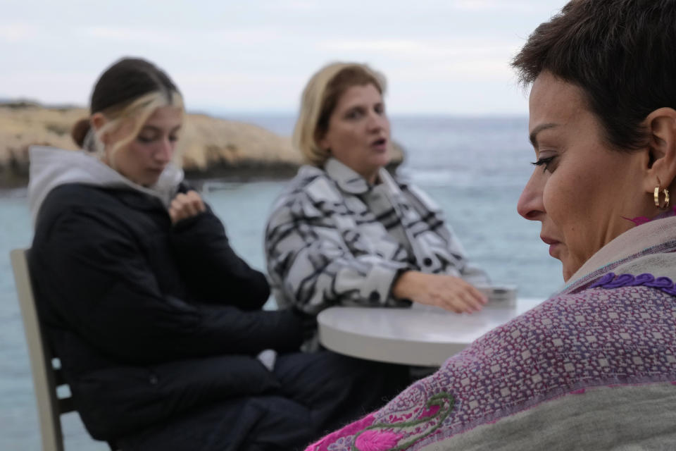 Nadine Kalache Maalouf, right, Celine Elbacha and Elbacha's daughter Morgane, left, sit at a seaside restaurant in the eastern coastal resort of Paralimni, Cyprus, on Wednesday, Dec. 22, 2021. They are among the thousands of Lebanese, including teachers, doctors and nurses who have left the country amid a devastating economic crisis that has thrown two thirds of the country’s population into poverty since October 2019. (AP Photo/Petros Karadjias)