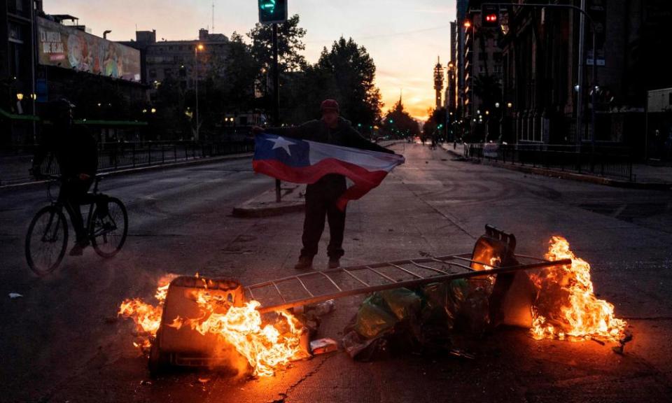 A man holds a Chilean flag in front of a barricade on Alameda Avenue in Santiago on Monday evening.