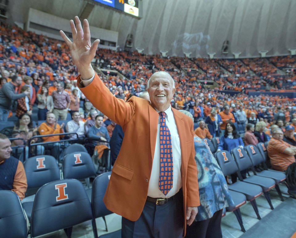 FILE - In this Dec. 2, 2015, file photo, former University of Illinois basketball coach Lou Henson acknowledges the crowd while taking his seat courtside during the dedication of the court in his name at the State Farm Center in Champaign, Ill. Henson, the basketball coach who led Illinois back into the national spotlight, has died at age 88. The school said Henson died Saturday, July, 25, 2020, and was buried on Wednesday, July 29, 2020. (AP Photo/Rick Danzl, File)