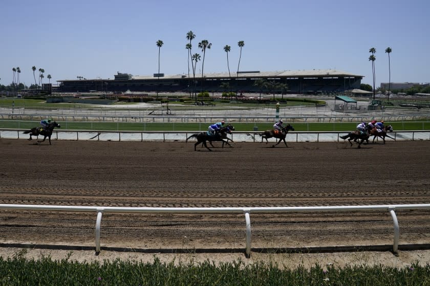 In this Friday, May 22, 2020 photo, jockeys wearing face masks ride in the first horse race past empty stands at Santa Anita Park in Arcadia, Calif. Horse racing returned to the track after being idled for one and a half months because of public health officials' concerns about the coronavirus pandemic. (AP Photo/Ashley Landis)