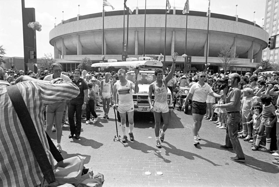 June 14, 1984: Olympic Torch being carried by Ray Tinnin of Houston, accompanied by David Vigil of San Fransisco, in front of the Fort Worth Convention Center.