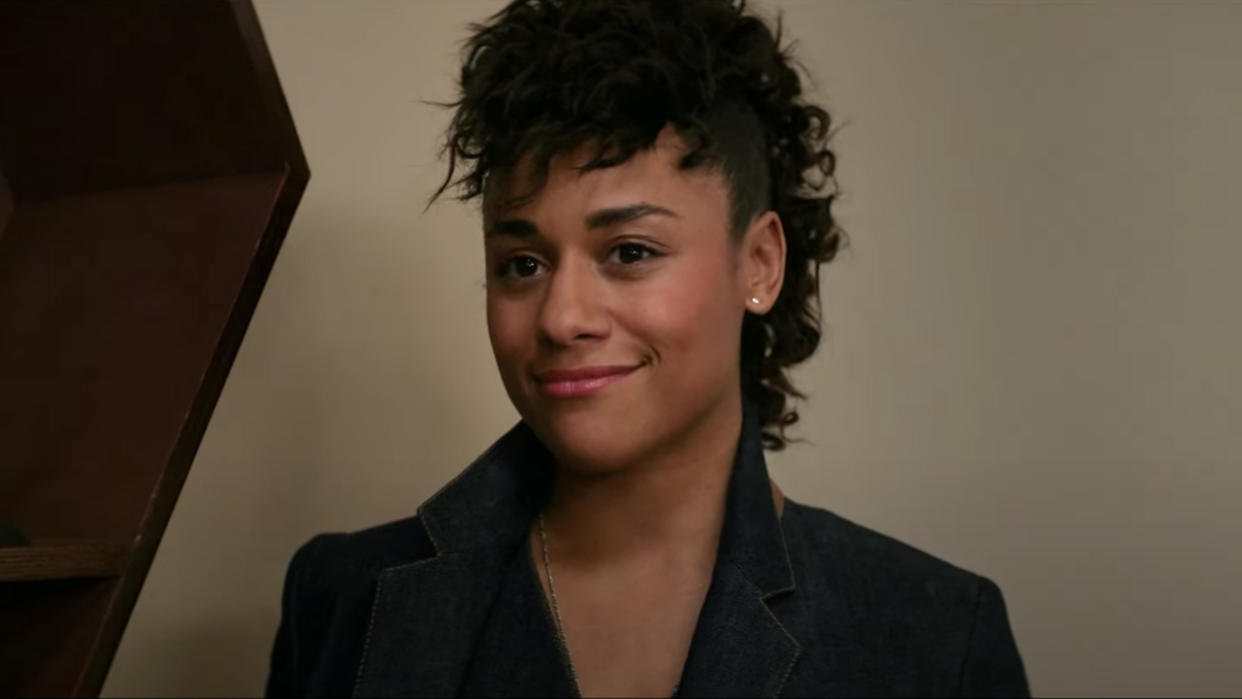  Ariana DeBose smiling in an office in Argylle. 