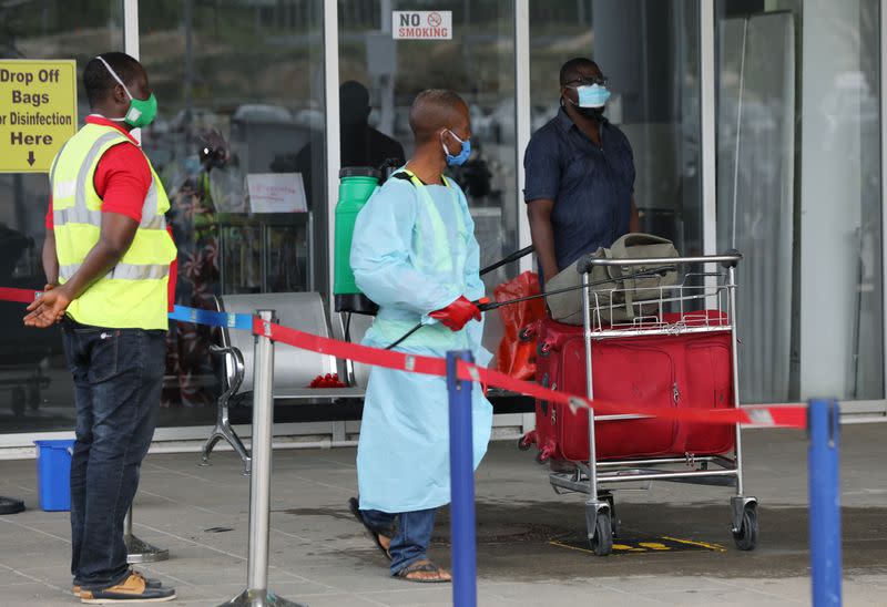 A worker carries disinfectant equipment outside the Nnamdi Azikiwe International Airport in Abuja