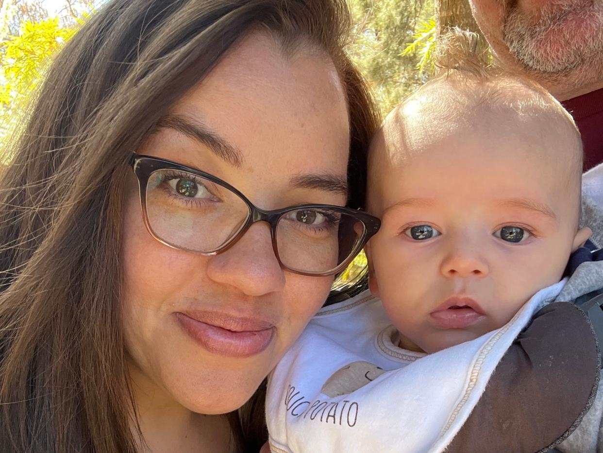 First-time mom Vanessa Wisniewski holds up her son, Silas, six months old. The child is wearing a bib.