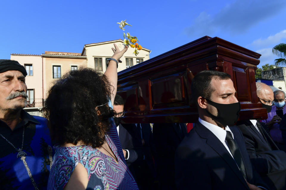 Pallbearers carry the coffin of late Greek composer, Mikis Theodorakis as a woman throws flowers, ahead of his burial, in Chania Crete island , Greece, Thursday, Sept. 9 2021. Theodorakis died Thursday, Sept. 2, 2021 at 96. He penned a wide range of work, from somber symphonies to popular TV and film scores, including for "Serpico" and "Zorba the Greek." He is also remembered for his opposition to the military junta that ruled Greece from 1967-1974, when he was persecuted and jailed and his music outlawed. (AP Photo/Michael Varaklas)