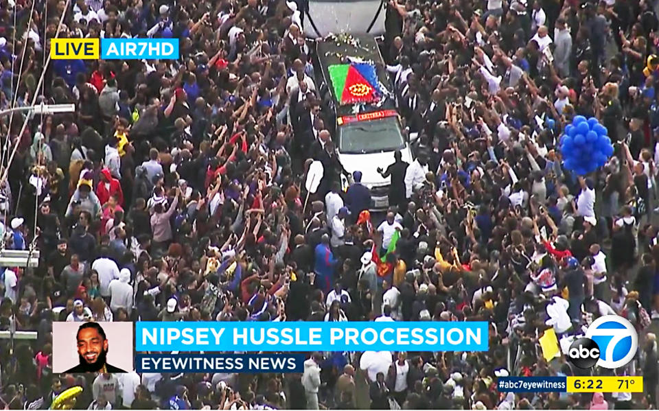 This photo taken from video provided by ABC7 shows thousands reaching toward the hearse carrying the body of rapper Nipsey Hussle, in a casket draped in the flag of his father’s native country, Eritrea in East Africa, as it moves past The Marathon clothing store in South Los Angeles Thursday, April 11, 2019. Hussle was shot to death March 31 while standing outside The Marathon, his clothing store, not far from where the rapper grew up. (ABC7 via AP)