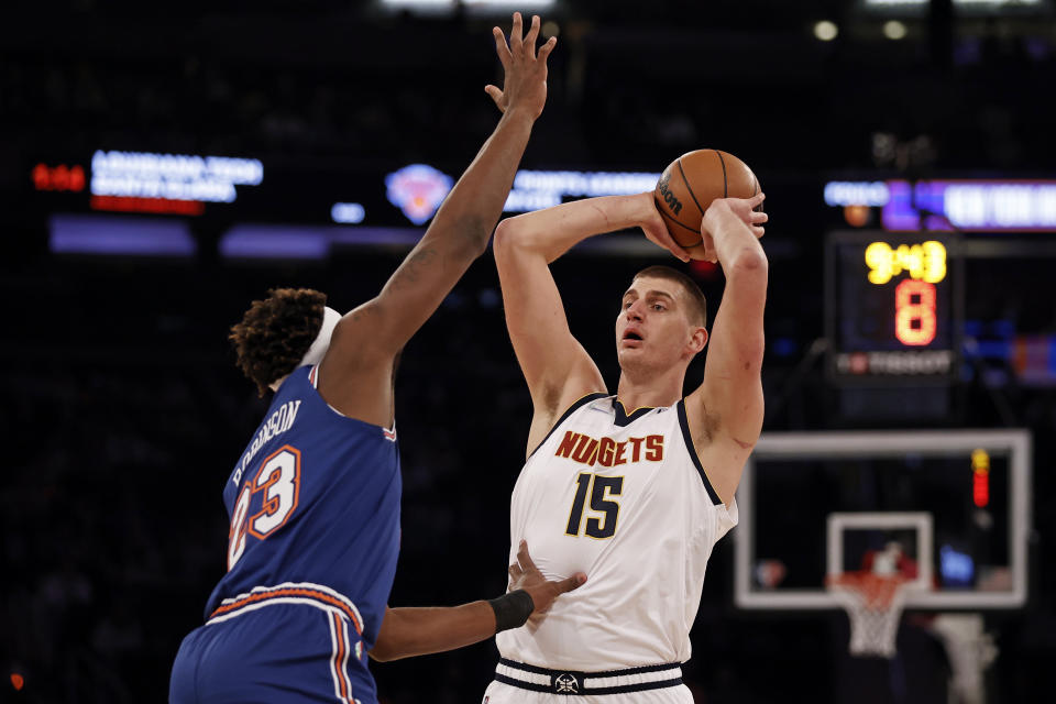 Denver Nuggets center Nikola Jokic (15) looks to pass around New York Knicks center Mitchell Robinson during the first half of an NBA basketball game Saturday, Dec. 4, 2021, in New York. (AP Photo/Adam Hunger)