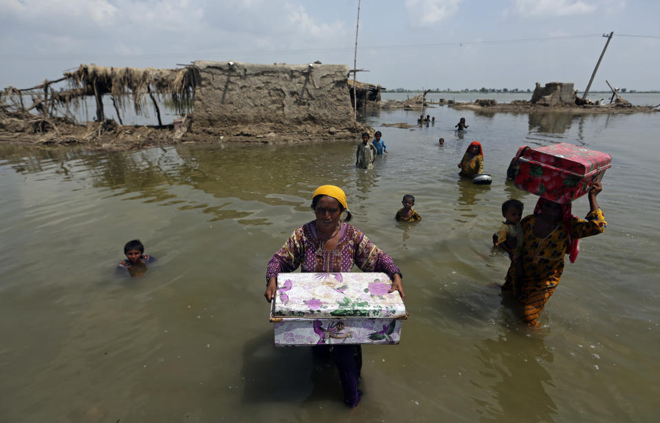 Women carry belongings salvaged from their flooded home after monsoon rains, in the Qambar Shahdadkot district of Sindh Province, of Pakistan, Tuesday, Sept. 6, 2022. (Fareed Khan/AP)