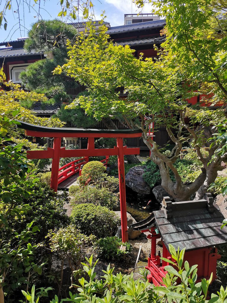 Visitors walk through lush Japanese gardens before reaching the restaurant building.