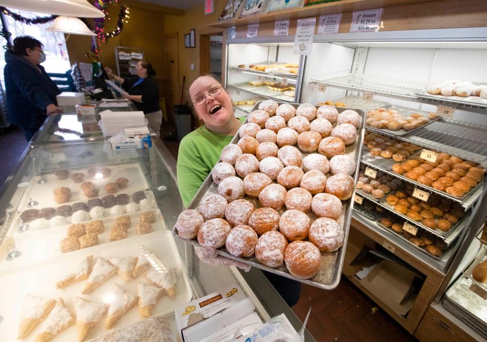 National Deli and Bakery cashier Mandy Norman moves a tray full of prune powdered paczki in preparation for paczki day in 2022.