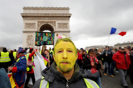 A protester wearing a yellow vest and with his face painted yellow walks down the Champs Elysees during a demonstration by the "yellow vests" movement in Paris, France, march 9, 2019. REUTERS/Philippe Wojazer