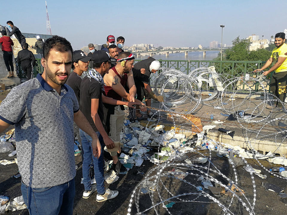 Iraqi anti-government protesters remove barriers set by security forces to close the Al-Sanak Bridge leading to the Green Zone during a demonstration in Baghdad, Iraq, Thursday, Oct. 31, 2019. Late Wednesday, hundreds of people headed to the Al-Sanak Bridge that runs parallel to the Joumhouriya Bridge, opening a new front in their attempts to cross the Tigris River to the Green Zone. Security forces fired volleys of tear gas that billowed smoke and covered the night sky. (AP Photo/Khalid Mohammed)