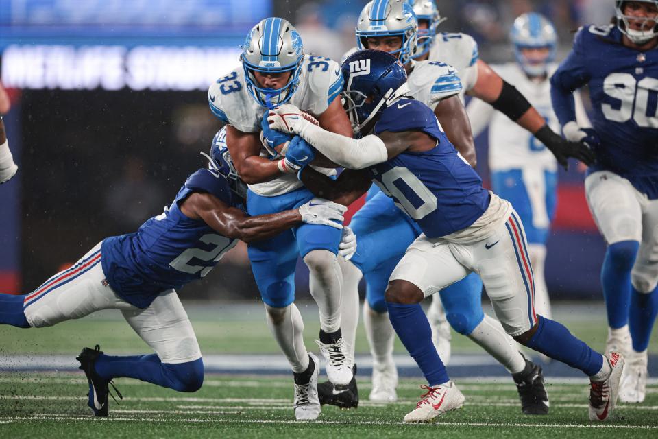 Aug 8, 2024; East Rutherford, New Jersey, USA; Detroit Lions running back Sione Vaki (33) carries the ball as New York Giants cornerback Darnay Holmes (30) and cornerback Alex Johnson (25) tackle during the first half at MetLife Stadium. Mandatory Credit: Vincent Carchietta-USA TODAY Sports