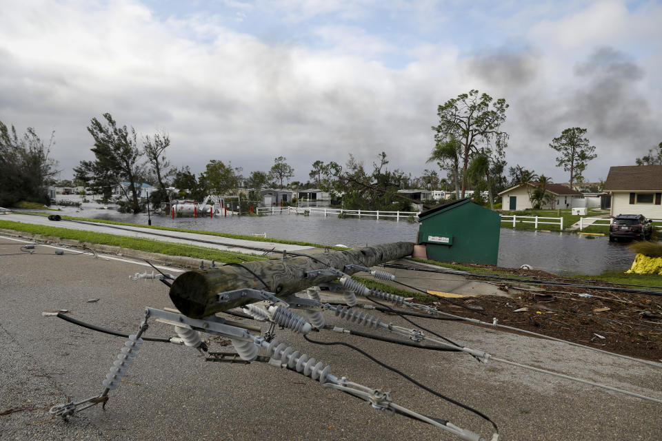 A broken utility pole lies on a street following Hurricane Ian.