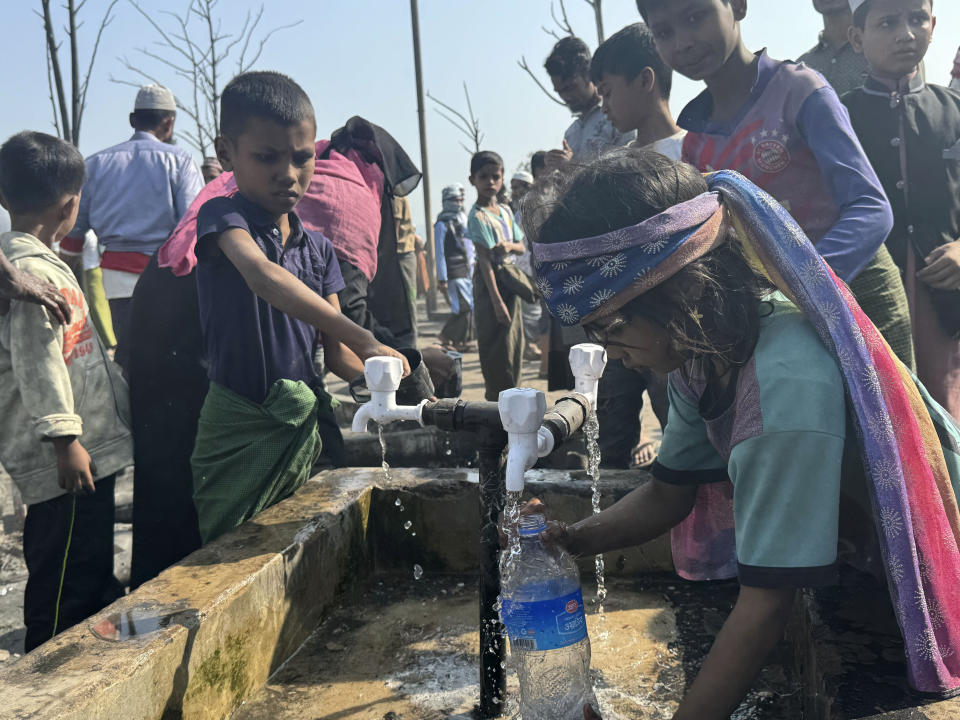 Rohingya refugee children collect drinking water after a midnight fire raced through their refugee camp at Kutupalong in Cox's Bazar district, Bangladesh, Sunday, Jan. 7, 2024. (AP Photo/ Shafiqur Rahman)