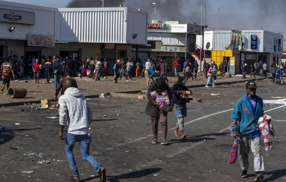 People carrying groceries looted at Letsoho Shopping Centre in Katlehong, east of Johannesburg, South Africa, Monday, July 12, 2021. Police say six people are dead and more than 200 have been arrested amid escalating violence during rioting that broke out following the imprisonment of South Africa's former President Jacob Zuma. (AP Photo/Themba Hadebe)