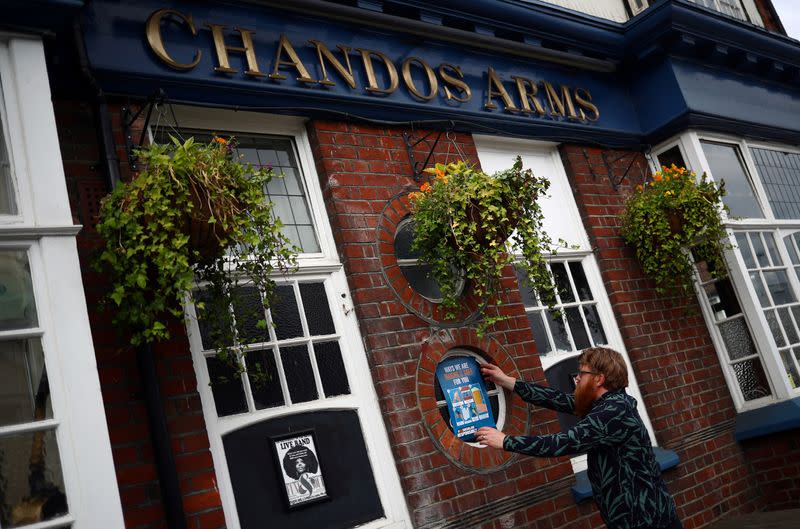 Landlord Are Kolltveit pins a safety sign to a window of the Chandos Arms pub ahead of pubs reopening following the coronavirus disease (COVID-19) outbreak, in London