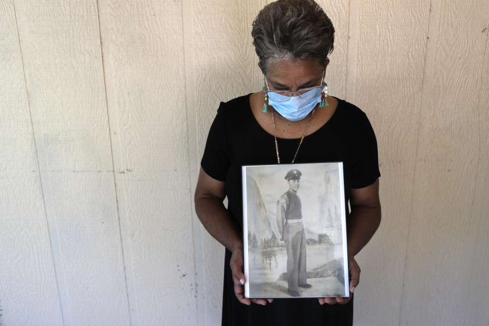 In this Monday, May 18, 2020 photo, Belvin Jefferson White poses with a portrait of her father Saymon Jefferson at Saymon's home in Baton Rouge, La. Belvin recently lost both her father and her uncle, Willie Lee Jefferson, to COVID-19. (AP Photo/Gerald Herbert)