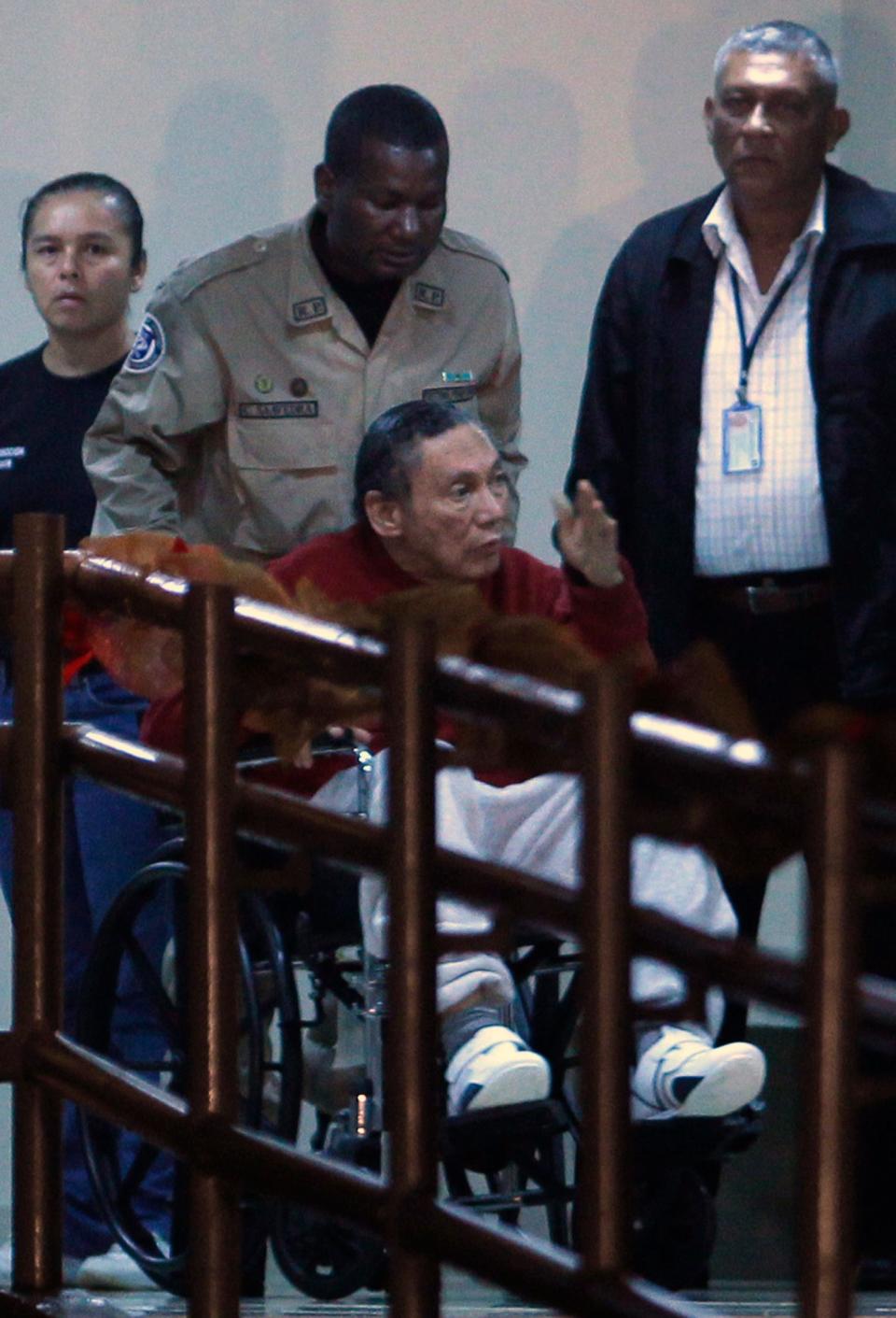 Manuel Noriega is wheeled by police inside El Renacer prison, 2011