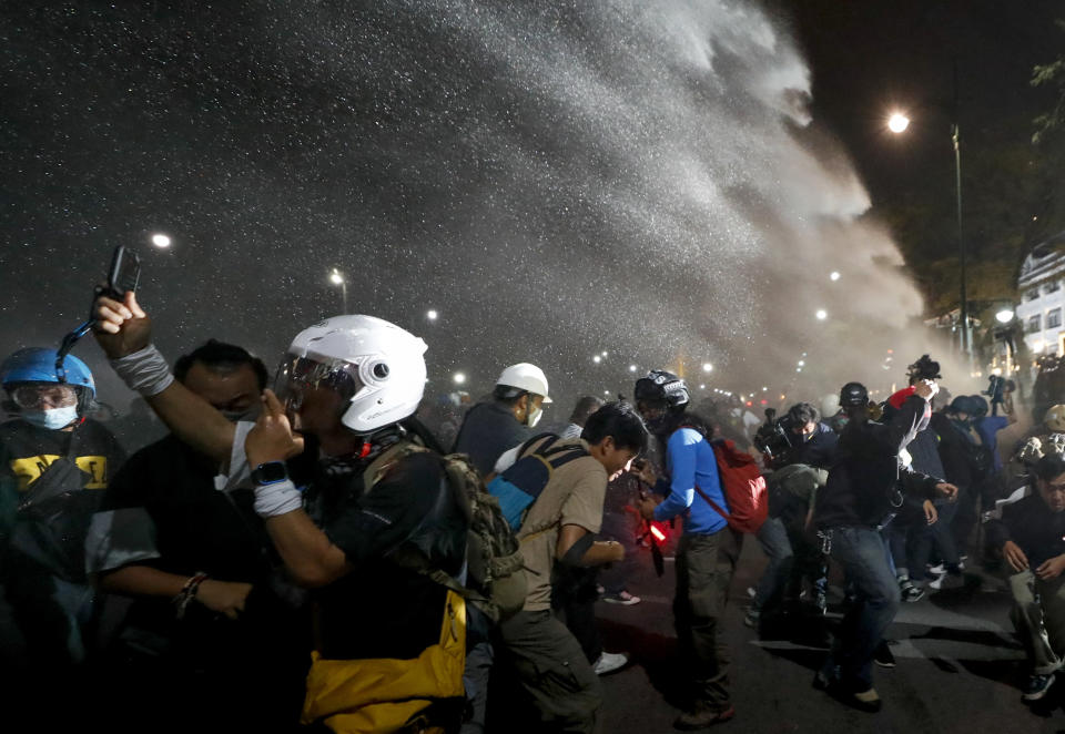 Police use water cannons to disperse pro-democracy protesters during a street march in Bangkok, Thailand Sunday, Nov. 8, 2020. The protesters continue to gather Sunday, led by their three main demands of Prime Minister Prayuth Chan-ocha's resignation, changes to a constitution that was drafted under military rule and reforms to the constitutional monarchy. (AP Photo/Sakchai Lalit)