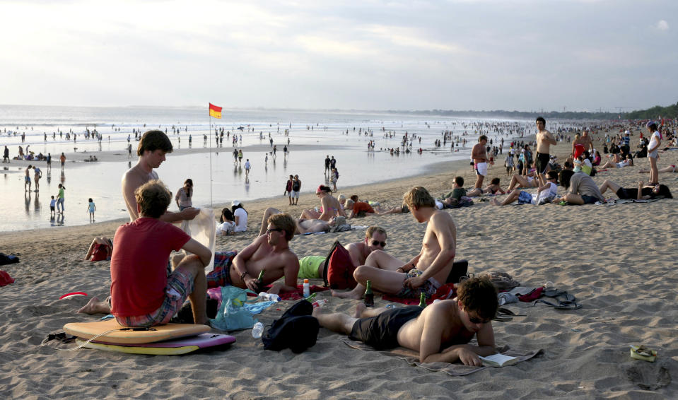 This Aug. 25, 2012 photo shows tourists relaxing on Kuta beach, Bali, Indonesia. It can be hard to find Bali's serenity and beauty amid the villas with infinity pools and ads for Italian restaurants. But the rapidly developing island's simple pleasures still exist, in deserted beaches, simple meals of fried rice and coconut juice, and scenes of rural life. (AP Photo/Firdia Lisnawati)