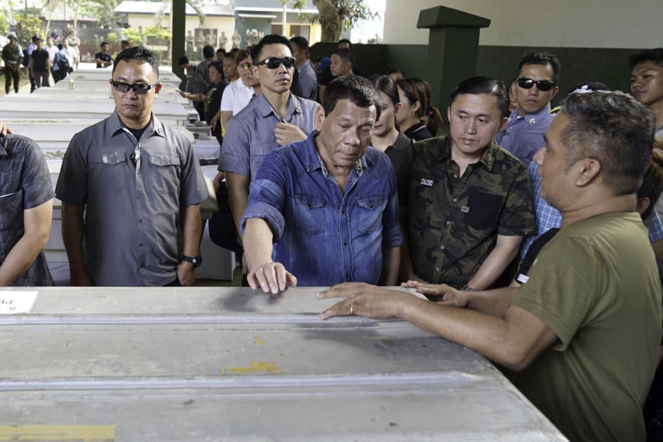 In this photo provided by Malacanang Palace, Philippine President Rodrigo Duterte, center, touches one of the caskets of victims of Sunday's bombings of a Roman Catholic Cathedral on Jolo, Sulu province in southern Philippines, during his visit Monday, Jan. 28, 2019. The attack occurred in the Sulu provincial capital on Jolo island, where Abu Sayyaf militants have carried out years of bombings, kidnappings and beheadings and have aligned themselves with the Islamic State group, which claimed responsibility for the attack.(Malacanang Palace Via AP)