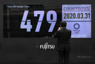 A man takes pictures of a countdown display for the Tokyo 2020 Olympics and Paralympics Tuesday, March 31, 2020, in Tokyo. The countdown clock is ticking again for the Tokyo Olympics. They will be July 23 to Aug. 8, 2021. The clock read 479 days to go. This seems light years away, but also small and insignificant compared to the worldwide fallout from the coronavirus. (AP Photo/Jae C. Hong)
