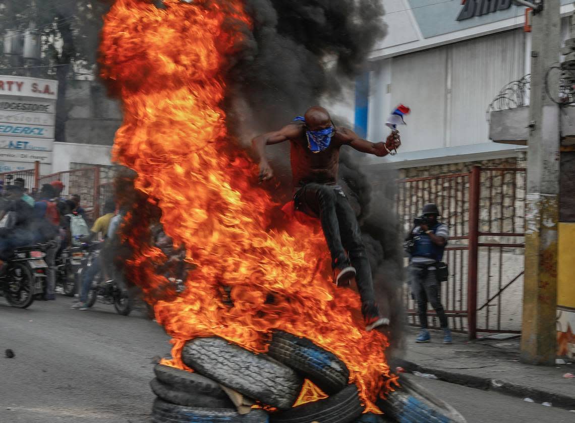 A protester jumps on burning tires during a protest against Haitian Prime Minister Ariel Henry in Port-au-Prince, Haiti, Monday, Feb. 5, 2024. (AP Photo/Odelyn Joseph)