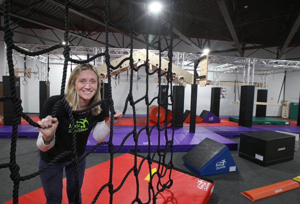 Owner Melissa McCarthy framed by cargo netting, inside at her newly opened USA Ninja Challenge in East Rochester.