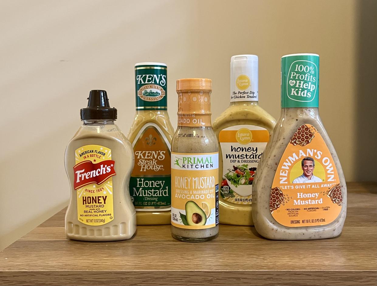 five brands of honey mustard sitting next to each other: French's, Newman's Own, Primal Kitchen, Ken's Steakhouse, and Laura Lynn
