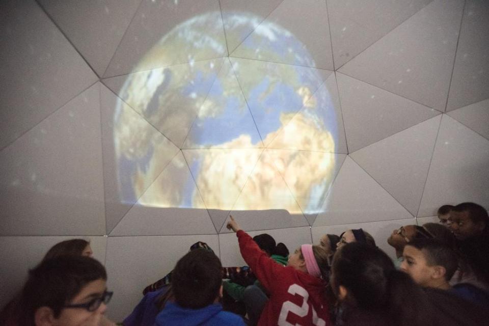 Carrie Reardon's K-5 STEM Lab class watches a scene from "Earth's Wild Ride," in the planetarium at the back of the room that she and her classes made out of cardboard as a three month project at Audubon Traditional Elementary School. Mar. 20, 2015