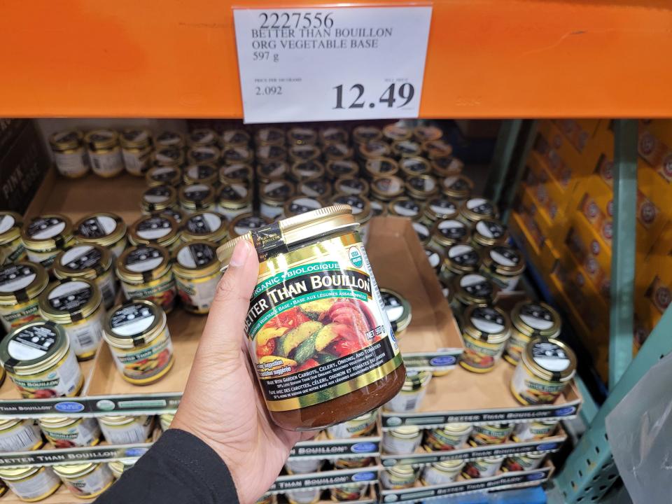 hand holding a jar of better than bouillon in front of the shelves at costco