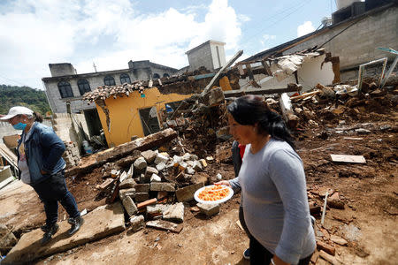 A woman holds a plate of food while walking past the debris of a house destroyed in an earthquake, in Tecomatlan, Mexico September 23, 2017. REUTERS/Edgard Garrido