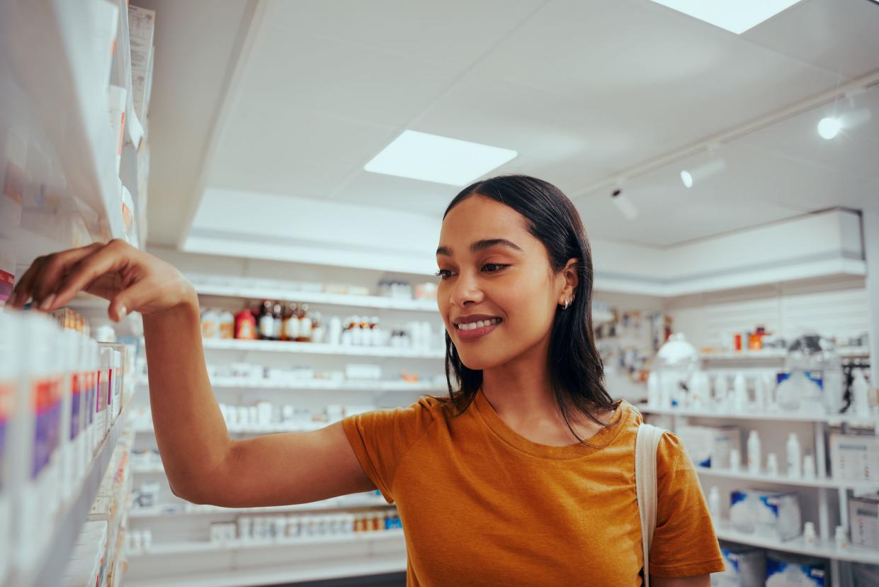 Portrait of smiling young woman in drugstore picking medicine