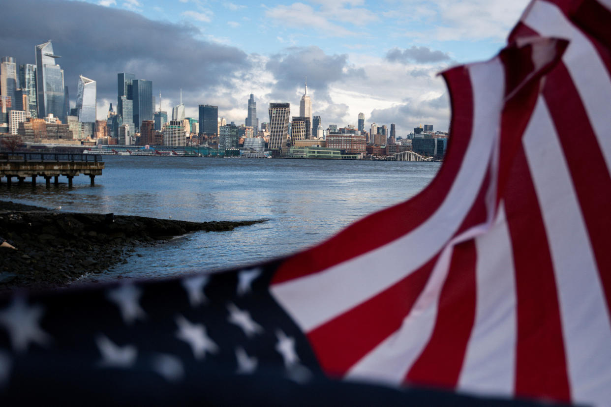 A U.S. flag waves during winds while storm clouds pass by the Empire State Building and middle Manhattan in New York City as seen from Hoboken, New Jersey, U.S., December 23, 2022. REUTERS/Eduardo Munoz