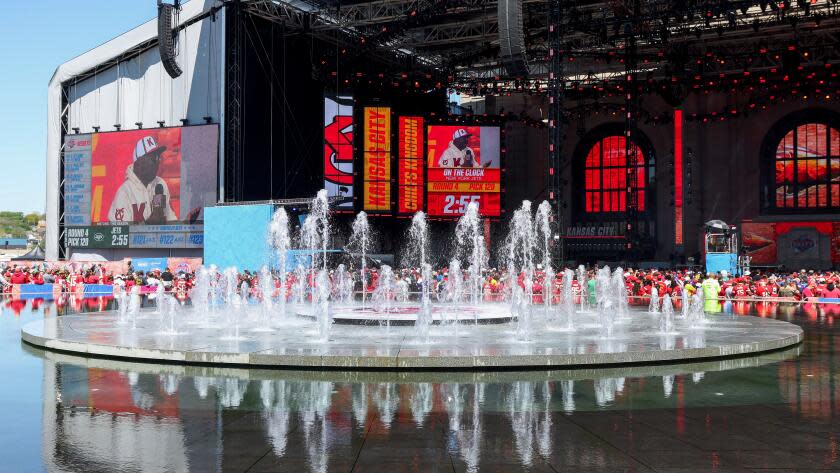 A wide view as fountains rise in front of the NFL Draft Theatre