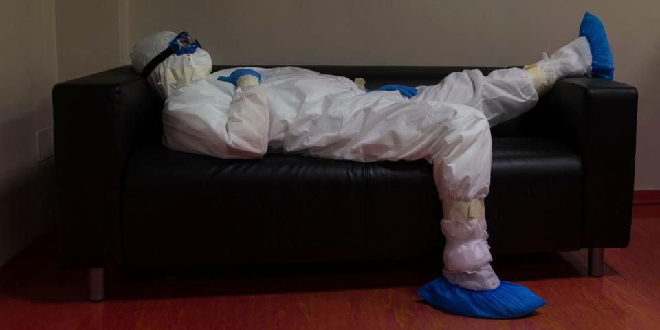 Doctor Giovanni Passeri relaxes in the doctor's lounge after completing a routine round of medical examinations during a night shift in his ward in the COVID-19 section of the Maggiore Hospital in Parma, northern Italy, Wednesday, April 8, 2020. Most of the times he is on a night shift the couch is the best Passeri can get to stretch out. A cardboard box at right holds envelopes with the medical charts of discharged patients. (AP Photo/Domenico Stinellis)