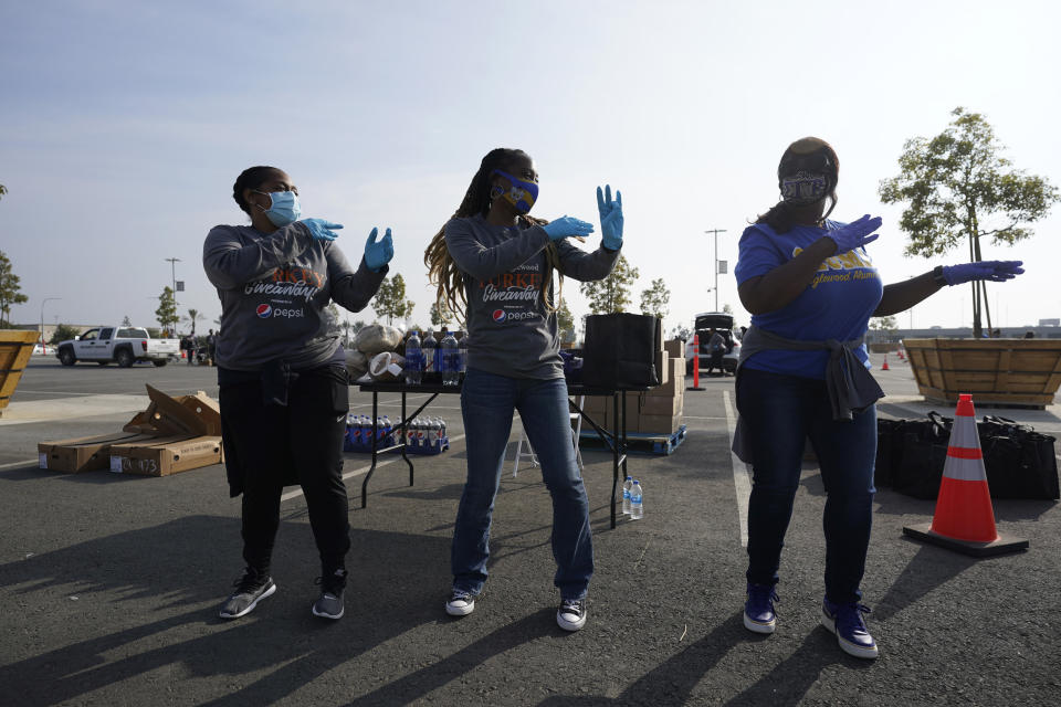 Volunteers dance while waiting to distribute food at SoFi Stadium ahead of Thanksgiving and amid the COVID-19 pandemic, Monday, Nov. 23, 2020, in Inglewood, Calif. (AP Photo/Marcio Jose Sanchez)