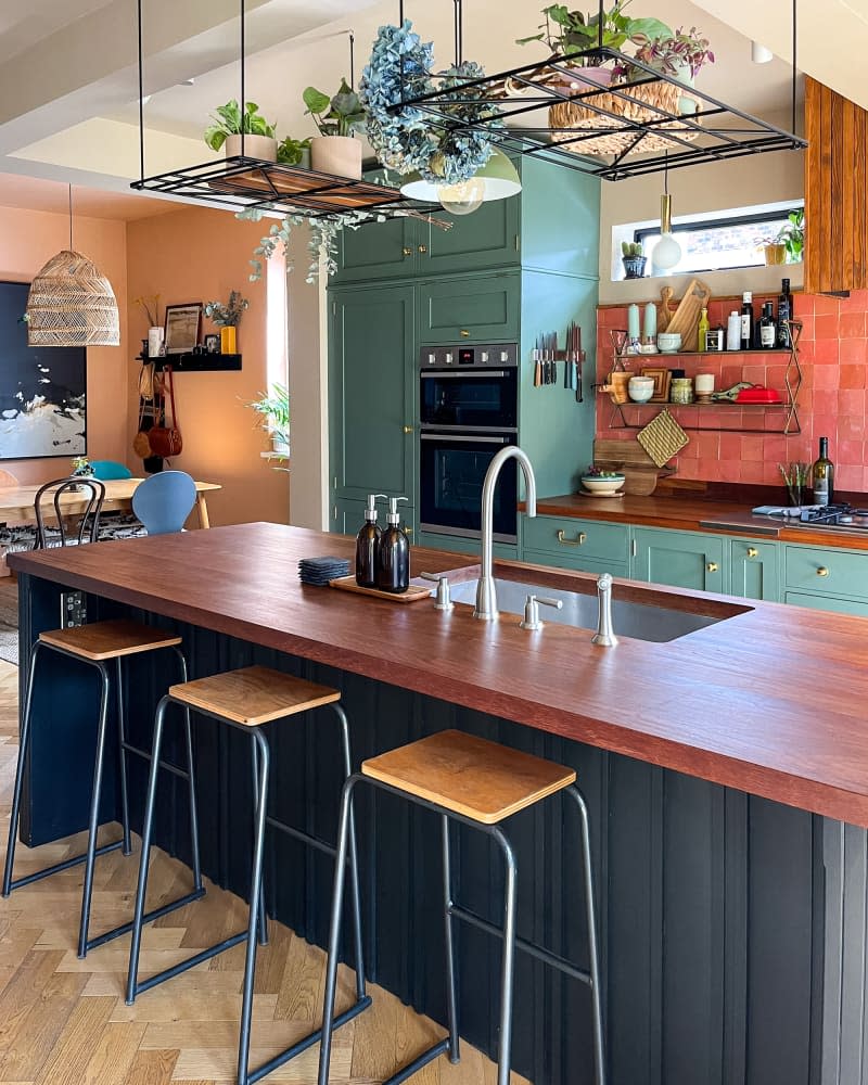 Butcher block island in pink and green newly renovated kitchen.