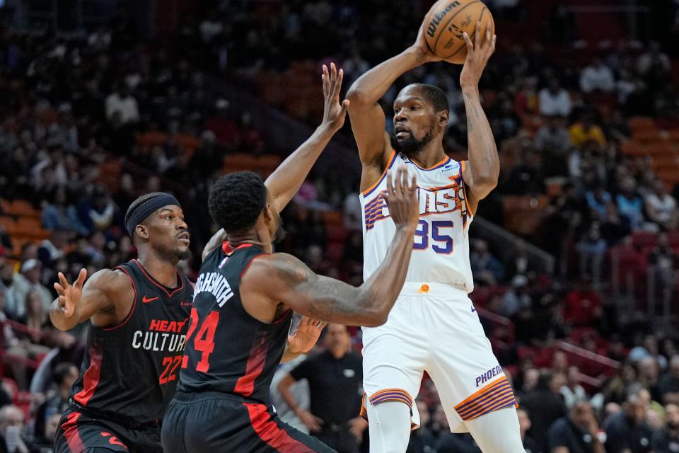 Phoenix Suns forward Kevin Durant (35) looks for an opening past Miami Heat forwards Jimmy Butler, left, and Haywood Highsmith (24) during the first half of an NBA basketball game, Monday, Jan. 29, 2024, in Miami.