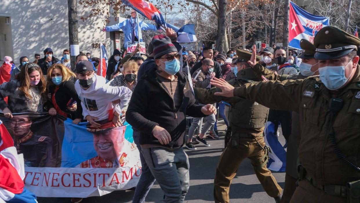 Unterstützer der kubanischen Regierung stoßen vor der kubanischen Botschaft auf Gegendemonstranten, die Plakate mit Bildern vom chilenischen Diktator Pinochet tragen.