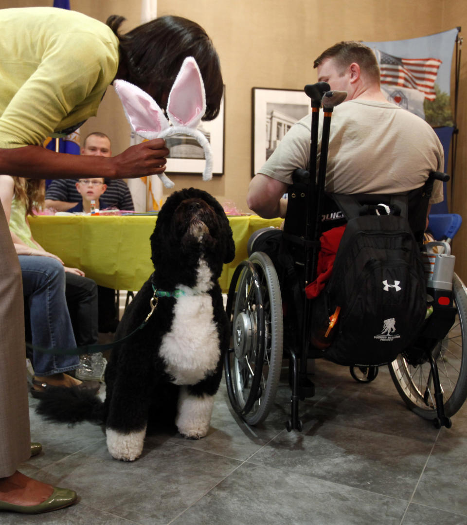 First lady Michelle Obama tries to put a pair of bunny ears on Bo, the Obama family dog, during a visit with families at Fisher House at Walter Reed National Military Medical Center in Bethesda, Md., Wednesday, April 4, 2012. The Fisher House program houses military families while a family member is receiving medical care. (AP Photo/Jacquelyn Martin)