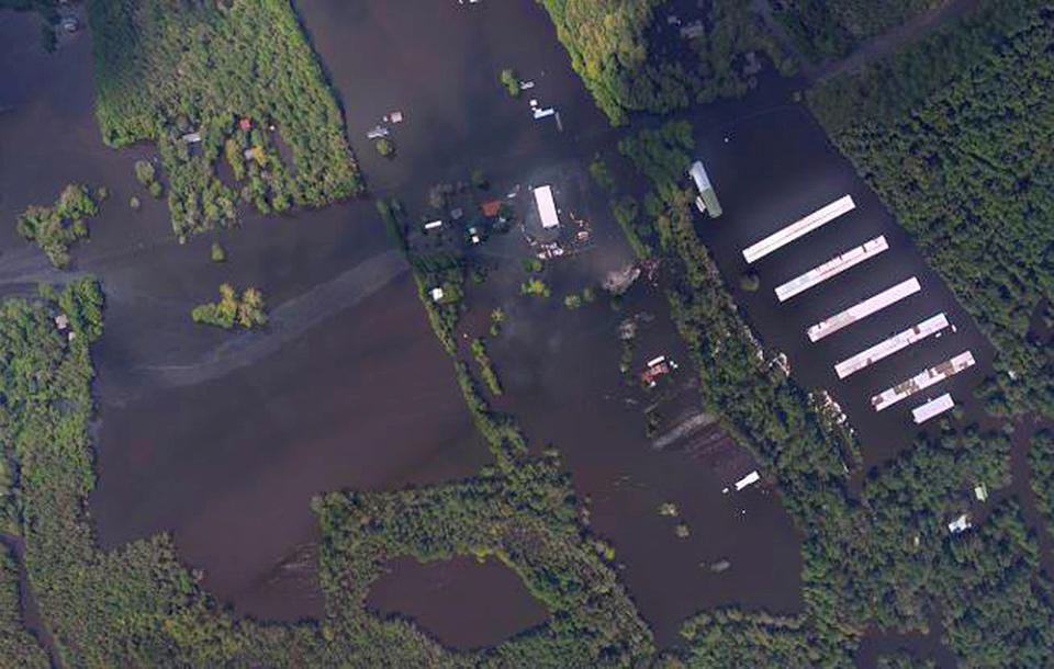 In this aerial photo taken Sept. 18, 2018 and released by the National Oceanic and Atmospheric Administration, an industrial site and a chicken farm outside Wallace, N.C., is seen that has been flooded by the nearby Northeast Cape Fear River following drenching rains from Hurricane Florence. (NOAA via AP)