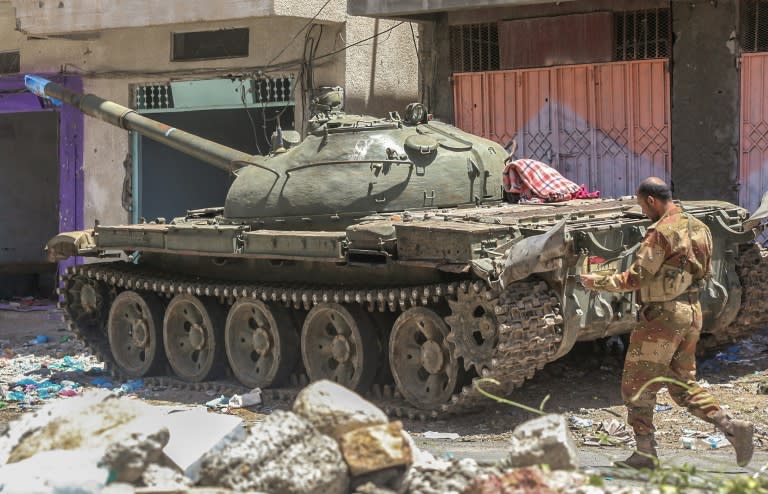 A Yemeni fighter loyal to the exiled president walks past a tank in the southwestern city of Taez on April 11, 2016