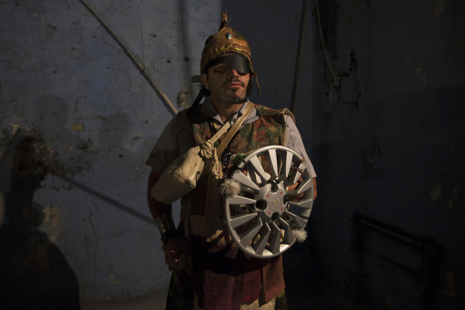 A man dressed as a Roman soldier uses a hubcap for a shield during the reenactment of the Passion of Christ on Good Friday during Holy Week celebrations in the Rocinha slum of Rio de Janeiro, Brazil, Friday, April 18, 2014. Roman Catholics throughout Latin America and the Caribbean are paying tribute to Jesus Christ in Holy Week traditions that go back centuries and range from religious processions to self-flagellation. (AP Photo/Hassan Ammar)