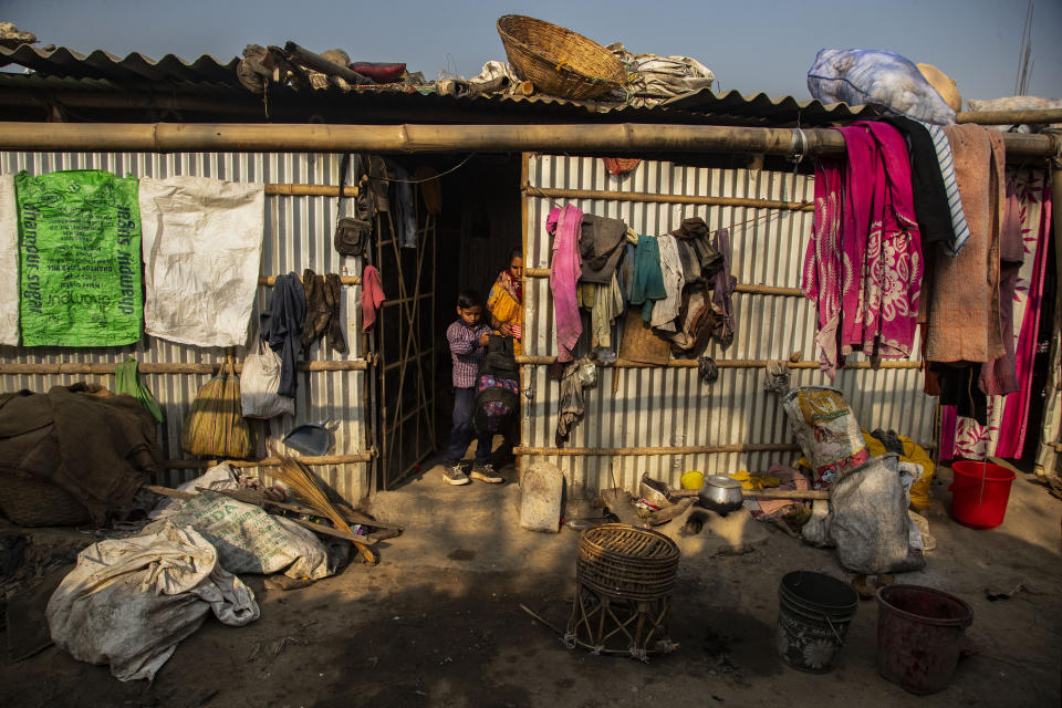 Imradul Ali, 10, center, takes his school bag from his mother Anuwara Beghum, 30, as he leaves for school from his rented kitchen cum bedroom on the outskirts of Gauhati, India, Friday, Feb. 5, 2021. Once school is done for the day, Ali, rushes home to change out of his uniform so that he can start his job as a scavenger in India’s remote northeast. Coming from a family of scavengers or “rag pickers," Ali started doing it over a year ago to help his family make more money. Ali says he doesn’t want to spend his life doing this, but he doesn’t know what the future holds. (AP Photo/Anupam Nath)