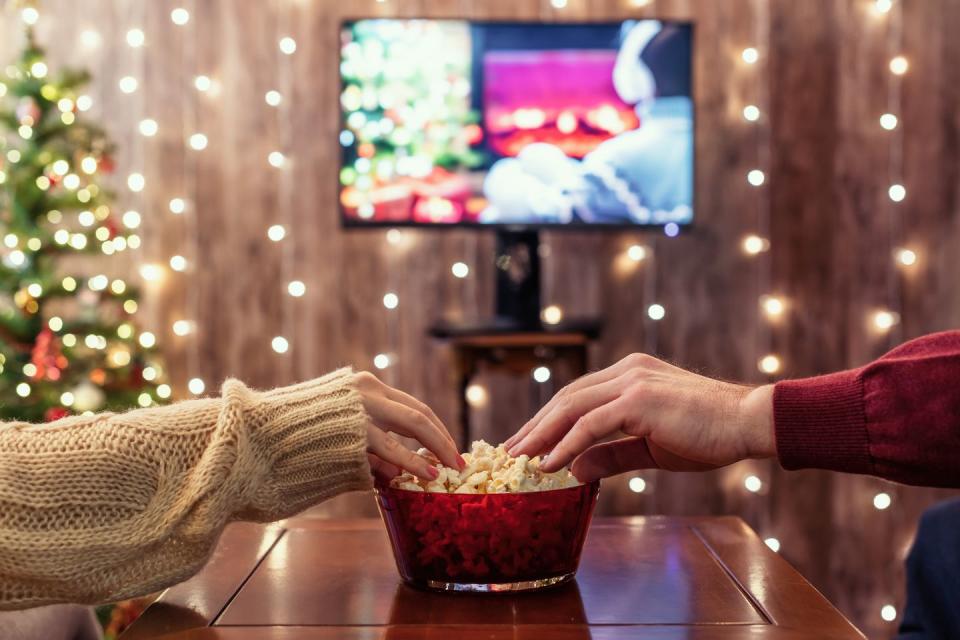 christmas eve couple watching tv and eating popcorn home cinema cropped close up