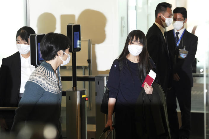 Japan's former Princess Mako, right, the elder daughter of Crown Prince Akishino, and her husband Kei Komuro, left, walk to board an airplane to New York Sunday, Nov. 14, 2021, at Tokyo International Airport in Tokyo. (AP Photo/Eugene Hoshiko)