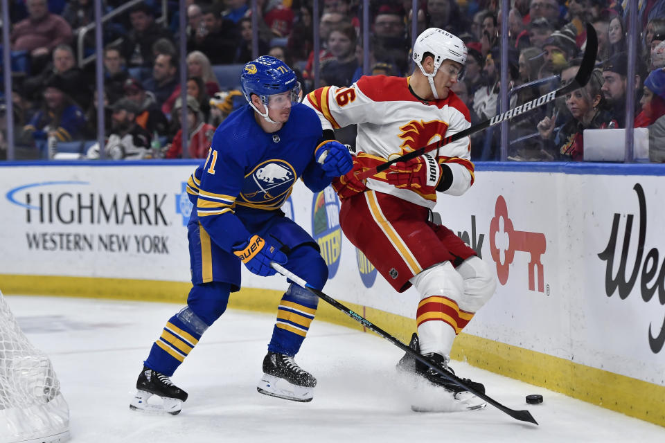 Calgary Flames defenseman Nikita Zadorov, right, battles for position over the puck with Buffalo Sabres left wing Victor Olofsson during the second period of an NHL hockey game in Buffalo, N.Y., Saturday, Feb. 11, 2023. (AP Photo/Adrian Kraus)
