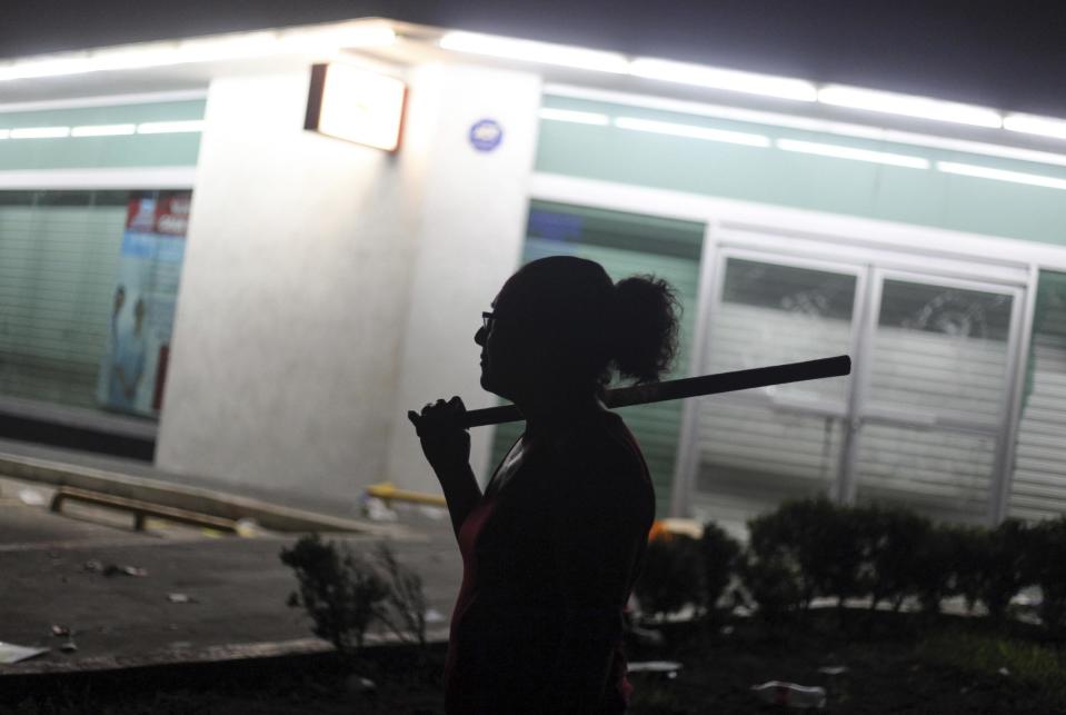 Una mujer sostiene un palo mientras ella y otros vecinos buscan evitar saqueos en la ciudad portuaria de Veracruz, México, la noche del jueves 5 de enero de 2017. (AP Foto/Félix Márquez)